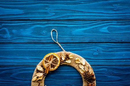 Creative, unusual Christmas wreath made of thread, dry fruits and nuts on blue wooden background top view space for textの写真素材