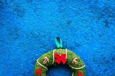 Christmas wreath traditional, classic type. Wreath made of spruce branches and red ribbons on blue background top view.の写真素材