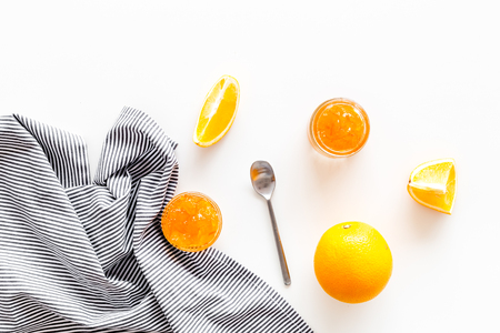 Fruit dessert. Orange jam in jar near slices of fresh oranges and spoon on white background top view copy spaceの写真素材