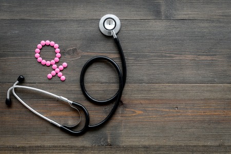 Female diseases concept. Stethoscope near female sign on dark wooden background top view copy spaceの写真素材