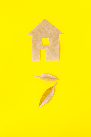 Eco friendly technologies for home concept. House silhouette made of craft paper on yellow background top view.の写真素材