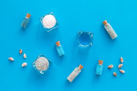 Dead sea cosmetics layout. Sea salt in bottles and bowls near small shells on blue background top viewの写真素材