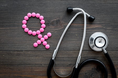 Female diseases concept. Stethoscope near female sign on dark wooden background top viewの写真素材