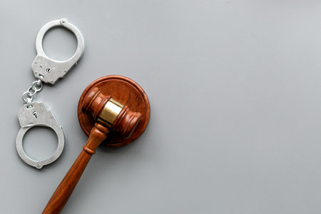 Crime concept. Metal handcuffs near judge gavel on grey background top view copy spaceの写真素材