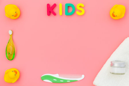 Hygiene items for the child. Bath accessories with yellow rubber duck on pink background top view copy space frame. Word KIDSの写真素材