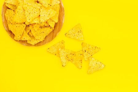 Snack for party. Make potato chips. Crispy potato chips on wooden cutting board on yellow background...