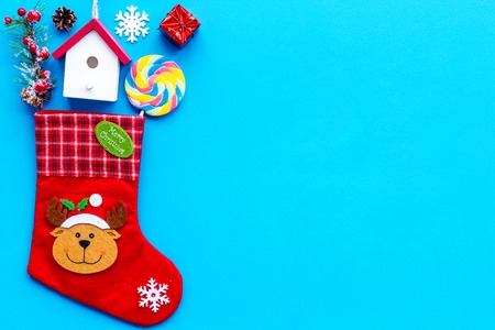 Christmas gift concept, christmas surprises. Traditional festive socks filled with gift box, sweets, winter decor on blue background top view space for textの写真素材