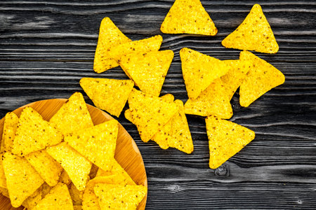 Snack for party. Make potato chips. Crispy potato chips on wooden cutting board on black wooden...