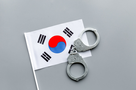 Violation of law, law-breaking concept. Metal handcuffs on Korean flag on grey background top viewの写真素材