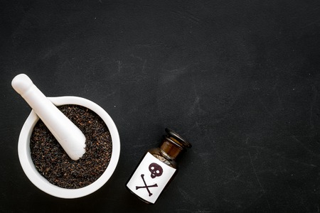 Prepare poison. Bottle with skull and crossbones near mortar and pounder on black background top view copy spaceの写真素材