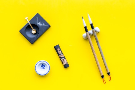 Accessories for chinese or japanese calligraphy. Special writting pen, ink on yellow background top viewの写真素材