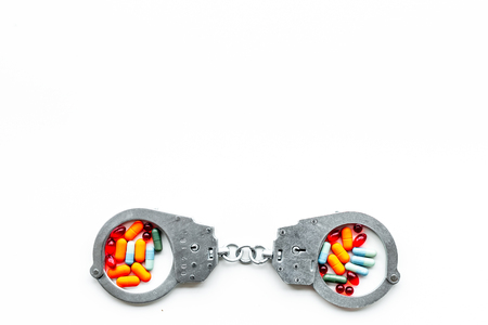 Arrest for illegal purchase, possession and sale drugs concept. Drugs as pills near handcuff on white background top view.の写真素材