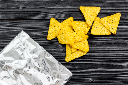 Nachos tortilla poured out of packing on black wooden background top view copy spaceの写真素材
