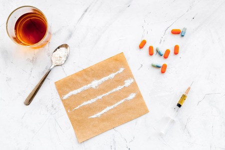 Take drugs, drugs addiction concept. White powder like heroine or cocaine, drug tracks pills, spoon, syringe on white stone background top viewの写真素材