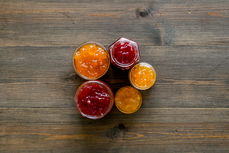 Set of sweet jams in glass jars on dark wooden background top view copy spaceの写真素材