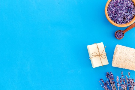 Spa set with lavender spa salt. Purple spa salt near dry lavender branches and washcloth on blue background top view.の写真素材