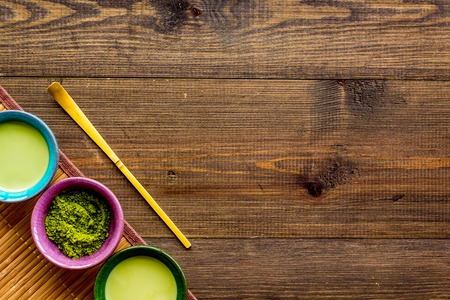 Brew matcha green tea. Matcha powder, ready matcha tea, whisk on dark wooden background top view.の写真素材