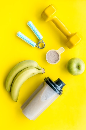 sport diet with protein nutrition and fitness equipment on yellow desk backgroundの写真素材