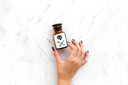 Dangerous addictions, dangerous entertainment. Poison. Female hand hold bottle with skull and...