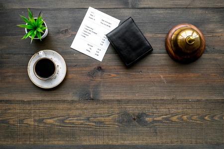 Pay the bill, pay at restaurant. Check near wallet, service bell, coffee on dark wooden background top view.の写真素材