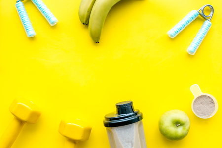 sport nutrition set with protein powder for cocktail and scoop on yellow desk background top view space for textの写真素材