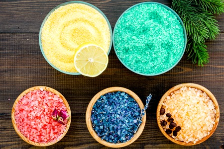 Aromas of bath salt. Lemon, coffee, rosemary, rose, lavender near bowls with colorful bath salt on dark wooden background top viewの写真素材