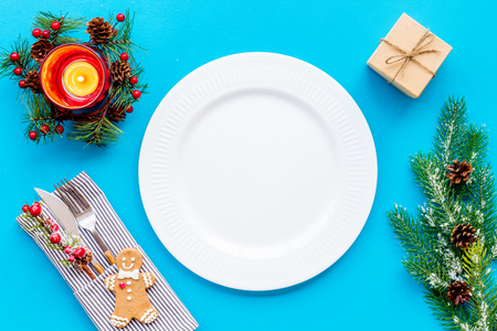 Christmas dinner decoration with gift box, plate and fir tree blue table background top view mock-upの写真素材