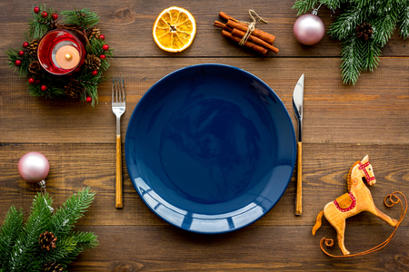 Christmas dinner decoration with gift box, plate and fir tree on wooden table background top view mock-upの写真素材