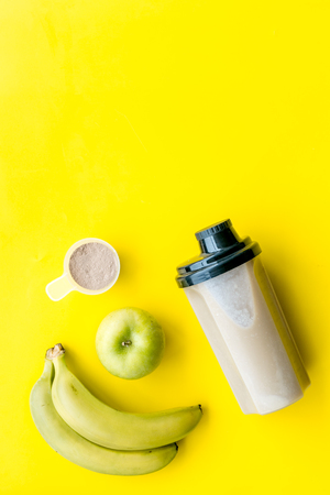 Sport nutrition set with protein powder for cocktail and scoop on yellow desk background top view space for textの写真素材