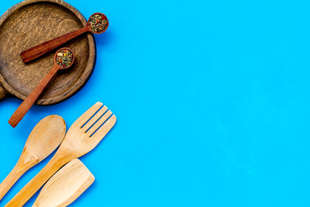 Fork, spoon, pan in woodenware set on blue table background top view space for text