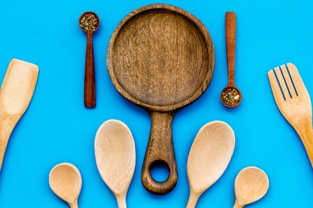 Woodenware set with pan, spoons and forks on blue background top view.の写真素材