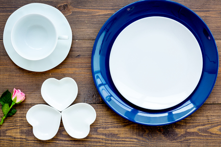 Simple color table setting for celebration with roses, blue plates and heart-shaped saucers on wooden kitchen table background top view mock up.の写真素材