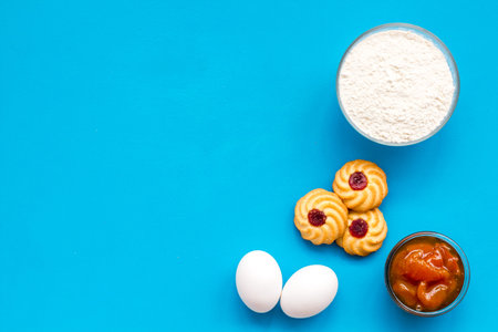 Ingredients for homemade cookies. Fresh cookies near flour, eggs on blue background top view copy spaceの写真素材
