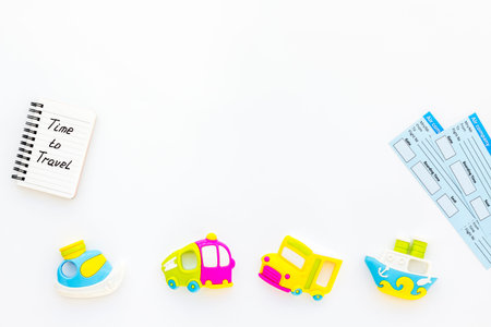 Time to travel. Accessories for traveling with children, tickets, notebook and toys on white desk...