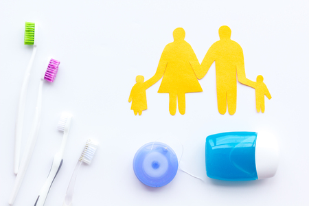 Daily oral hygiene for family. Toothbrush, dental floss and family figures on white table background top viewの写真素材