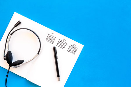 Desk of musician for songwriter work with headphones and notes on blue background top view mockupの写真素材