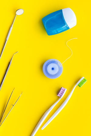 Daily oral hygiene for family. Toothbrush, dental floss and dentist instruments on yellow table background top viewの写真素材