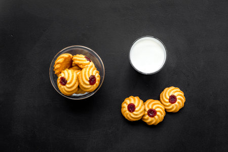 Children tradition evening dessert. Milk and homemade cookies on black background top view.
