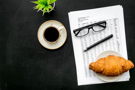 Business lunch with croissant and black coffee on work desk on blackの写真素材