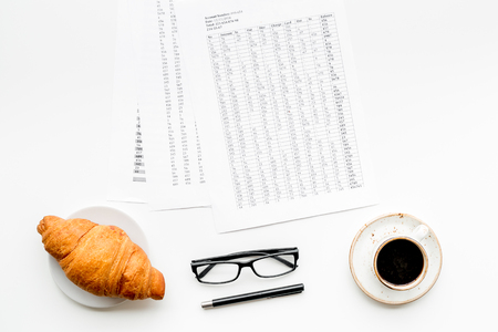 Breakfast in office with croissant and black coffee on the work desk with documents and glasses on whiteの写真素材