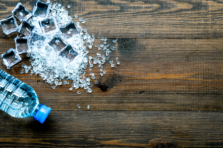pile of ice cubes and plastic bottle on wooden bar table top view mock-upの写真素材