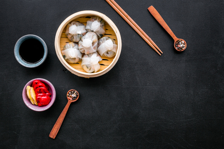 Dinner in Chinese restaurant with dim sum, sticks and tea on black background top view space for textの写真素材