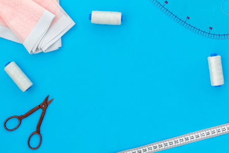 Tailor shop with thread, scissors, fabric. Sewing as hobby. Blue background top view mockup