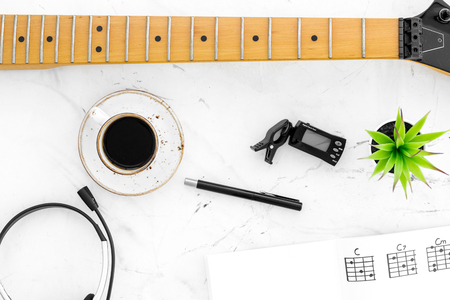 Desk of musician for songwriter work with headphones, keyboard, guitar and notes marble background top viewの写真素材