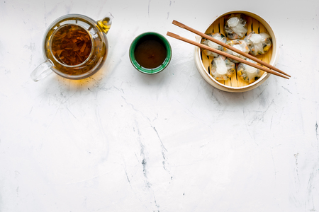 Chinese steamed dumplings Dim Sum in bamboo steamer with tea on marble background top view mock upの写真素材
