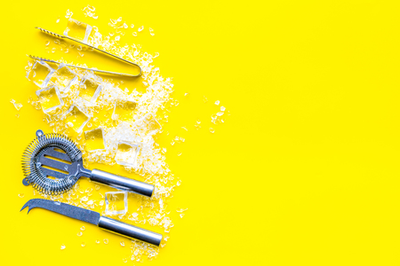 Bar desk with ice cubes and barman instruments on yellow background top view space for textの写真素材