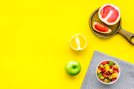 Healthy diet concept. Fruit salad near fresh fruits on yellow background top view copy spaceの写真素材