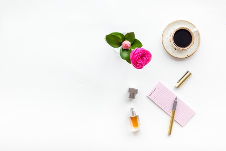 Home work desk, feminine workplace. Notebook and stationery near pink flowers and coffee on white background top view space for textの写真素材