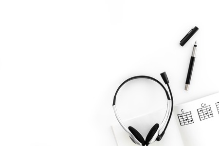 Desk of musician for songwriter work with headphones and notes white background top view mockupの写真素材