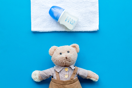 Handmade toys for newborn baby. Teddy bear. Feeding bottle with milk. Blue background top viewの写真素材